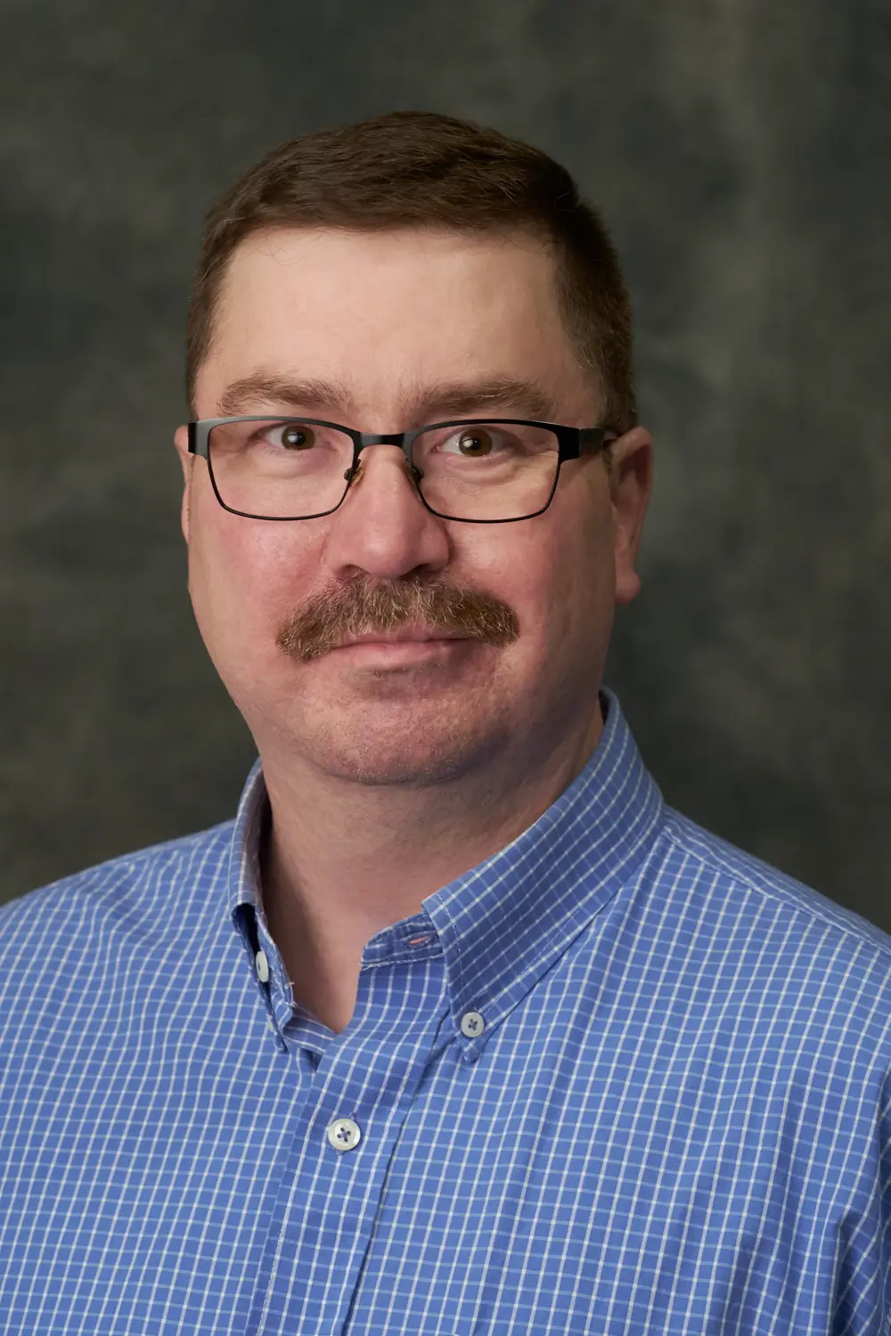Mark Miller, Realtor with The Signature Group, in a dark suit and tie against a grey studio backdrop